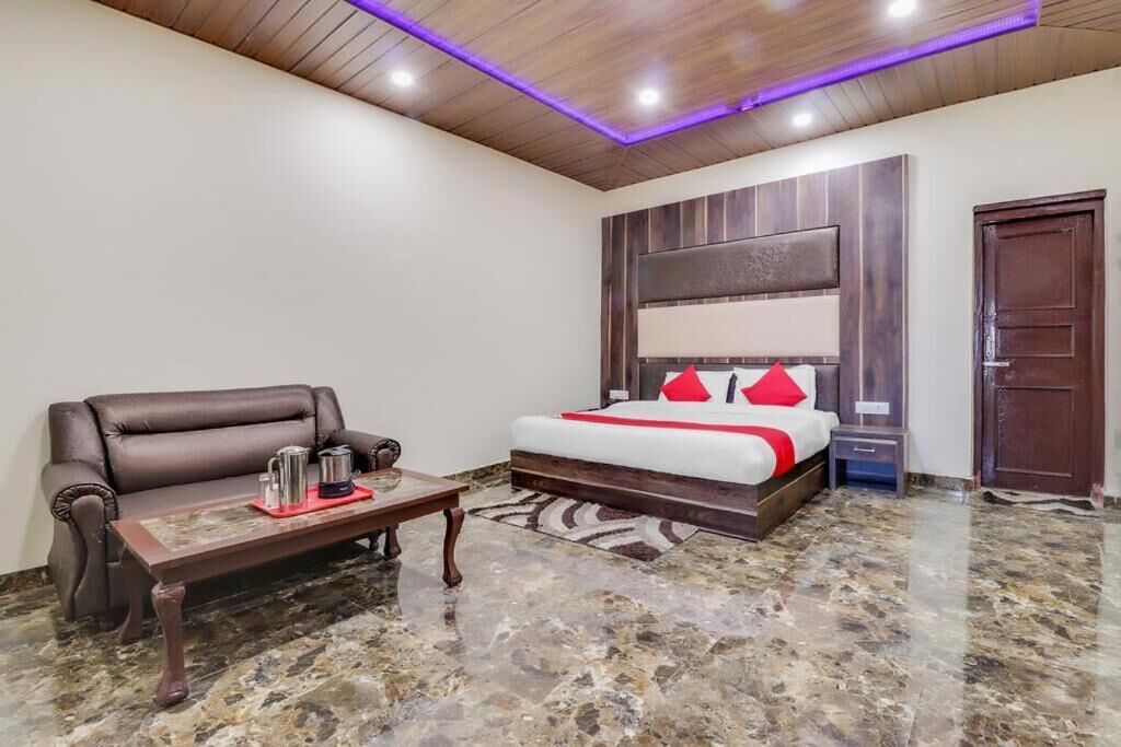 Habitación de hotel con cama, sofá, mesa de centro y techo de madera con iluminación LED.