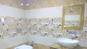 Un bany amb vàter, rentapla i mirall. Les parets tenen un mosaic amb motius florals.