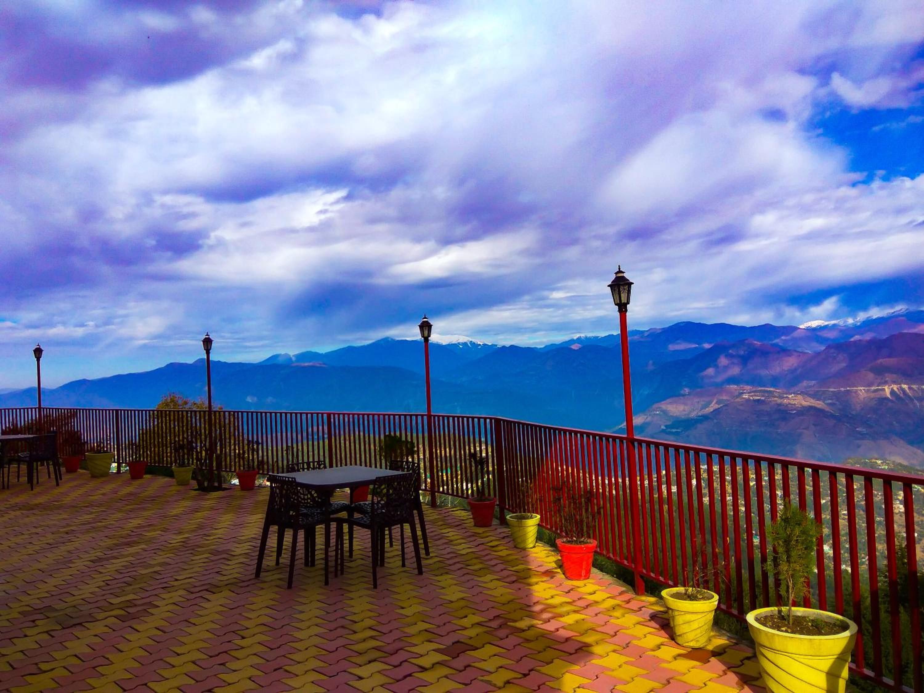 Eine Terrasse mit Tisch und Stühlen, Blumentöpfen und Blick auf Berge.