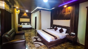 Habitación de hotel con una cama grande, un área de descanso y un baño visible a través de una puerta abierta.