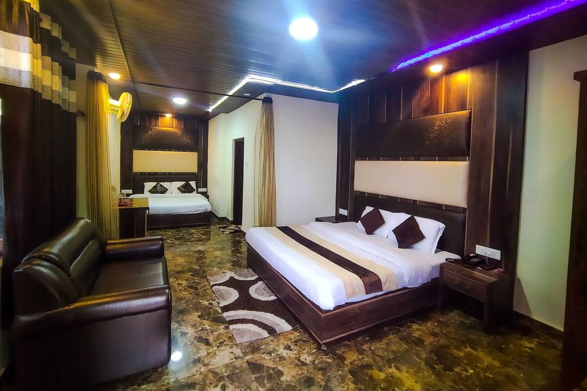 Una habitación de hotel con una cama grande, un sofá, un escritorio con teléfono y un espejo.