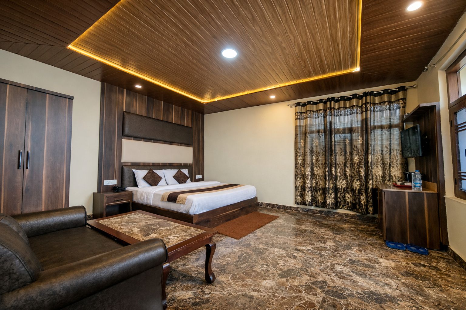 Una habitación de hotel con cama, sofá, escritorio y televisor.