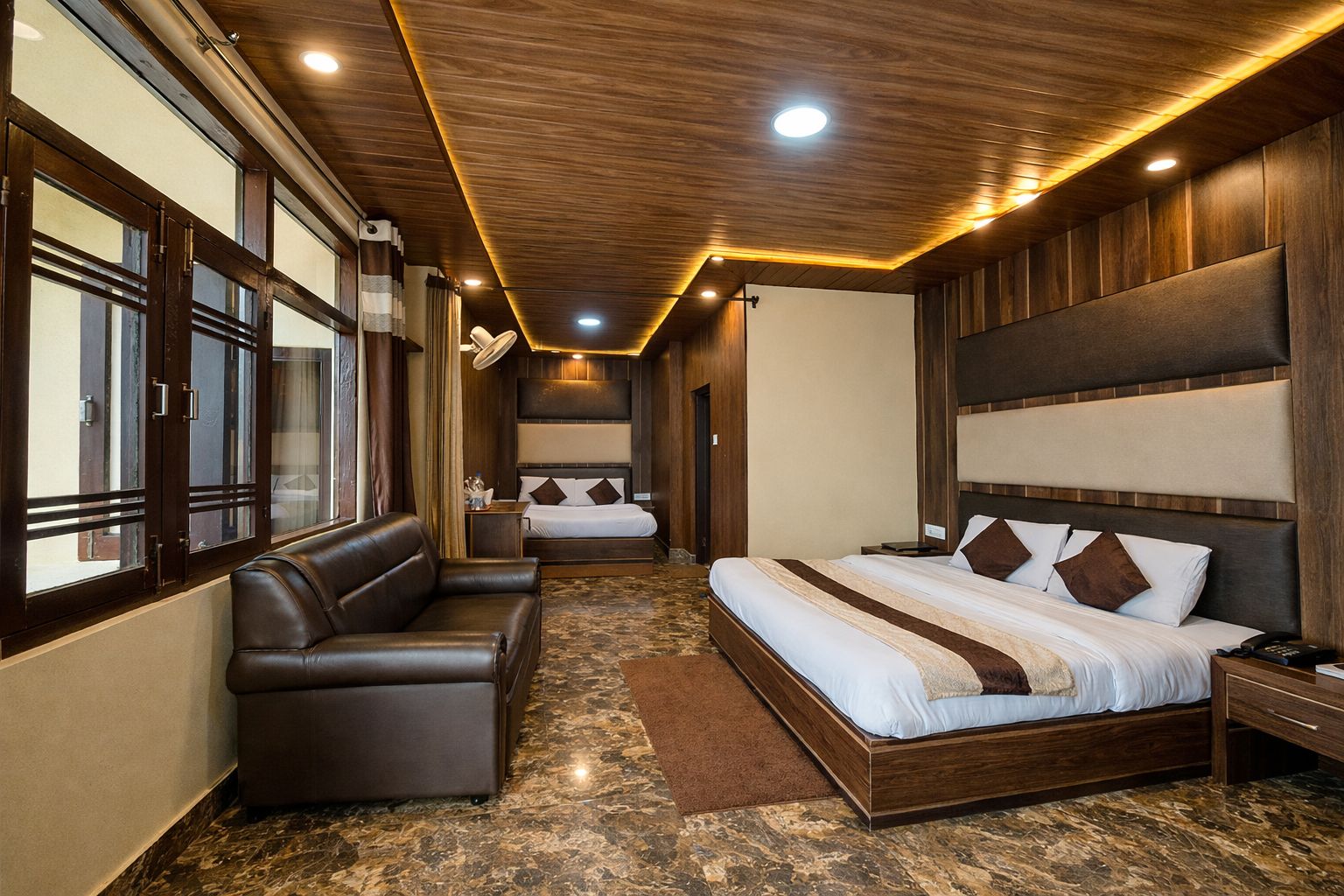 A hotel room with a large bed, a sofa, and a view through a window.