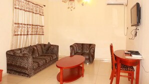 A living room with a sofa, two armchairs, a coffee table, and a TV. - Carlcon Hotel (Calabar)