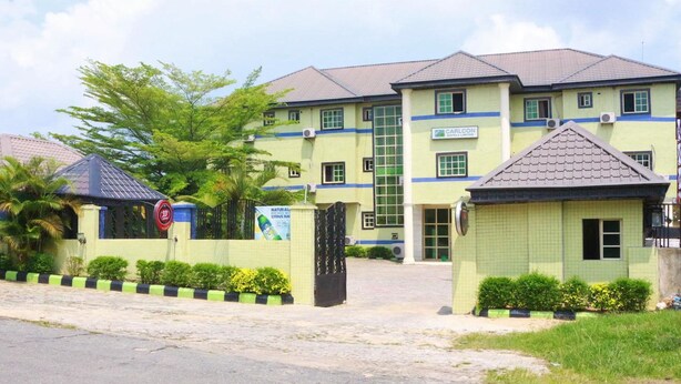 A hotel with a green facade, multiple windows, and a gated entrance. - Carlcon Hotel (Calabar)