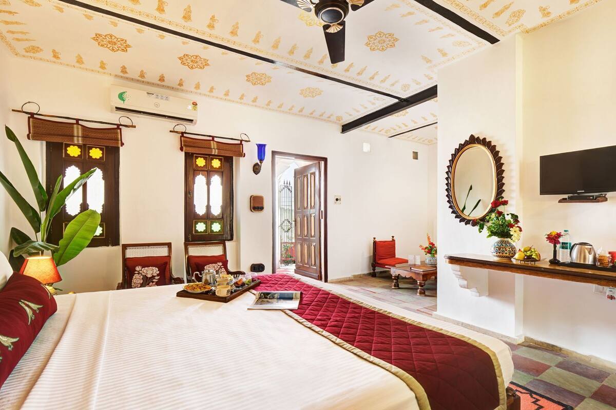 A hotel room with a bed, a desk, a mirror, and a television.