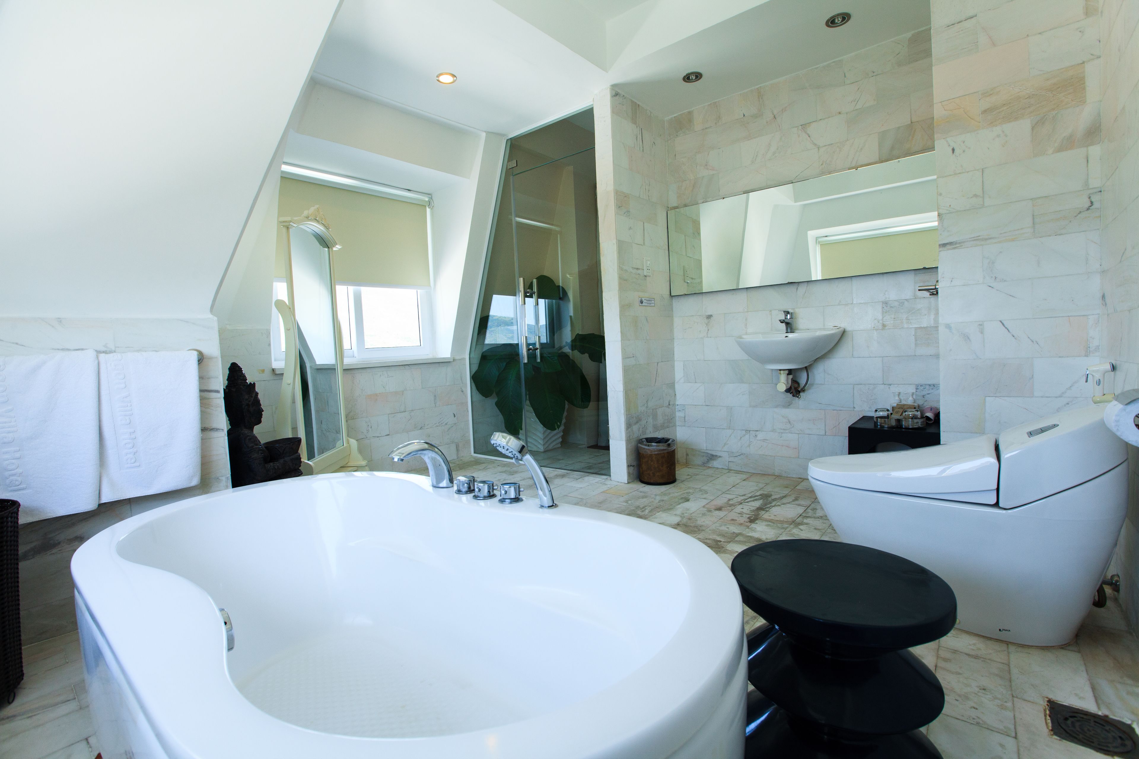 Un bagno moderno con una grande vasca, un WC separato, un lavandino e uno specchio.