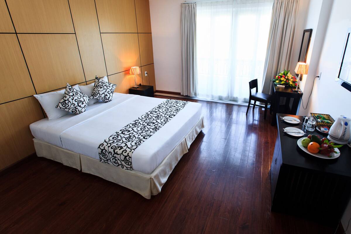A hotel room with a large bed, a desk with a chair, and a TV.