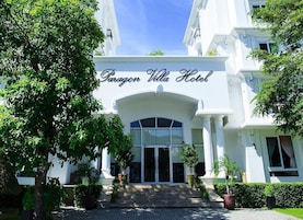 The Paragon Villa Hotel entrance with a grand archway, steps leading up to the doors, and potted plants around.