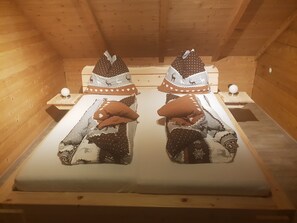 A wooden cabin room with two beds, each with a pillow featuring a deer pattern. - Appartementhaus Gugganig (Flattach)