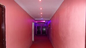 A narrow hallway with red walls and a red carpet, leading to a door at the end. - Time View Hotel & Suites (Lagos)