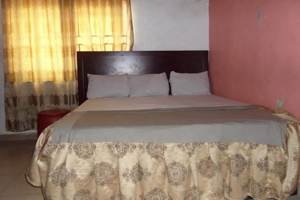 Un dormitorio con cama, cortinas y un equipo de aire acondicionado.