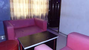 A room with a pink sofa, a small table, and a red stool. - Time View Hotel & Suites (Lagos)