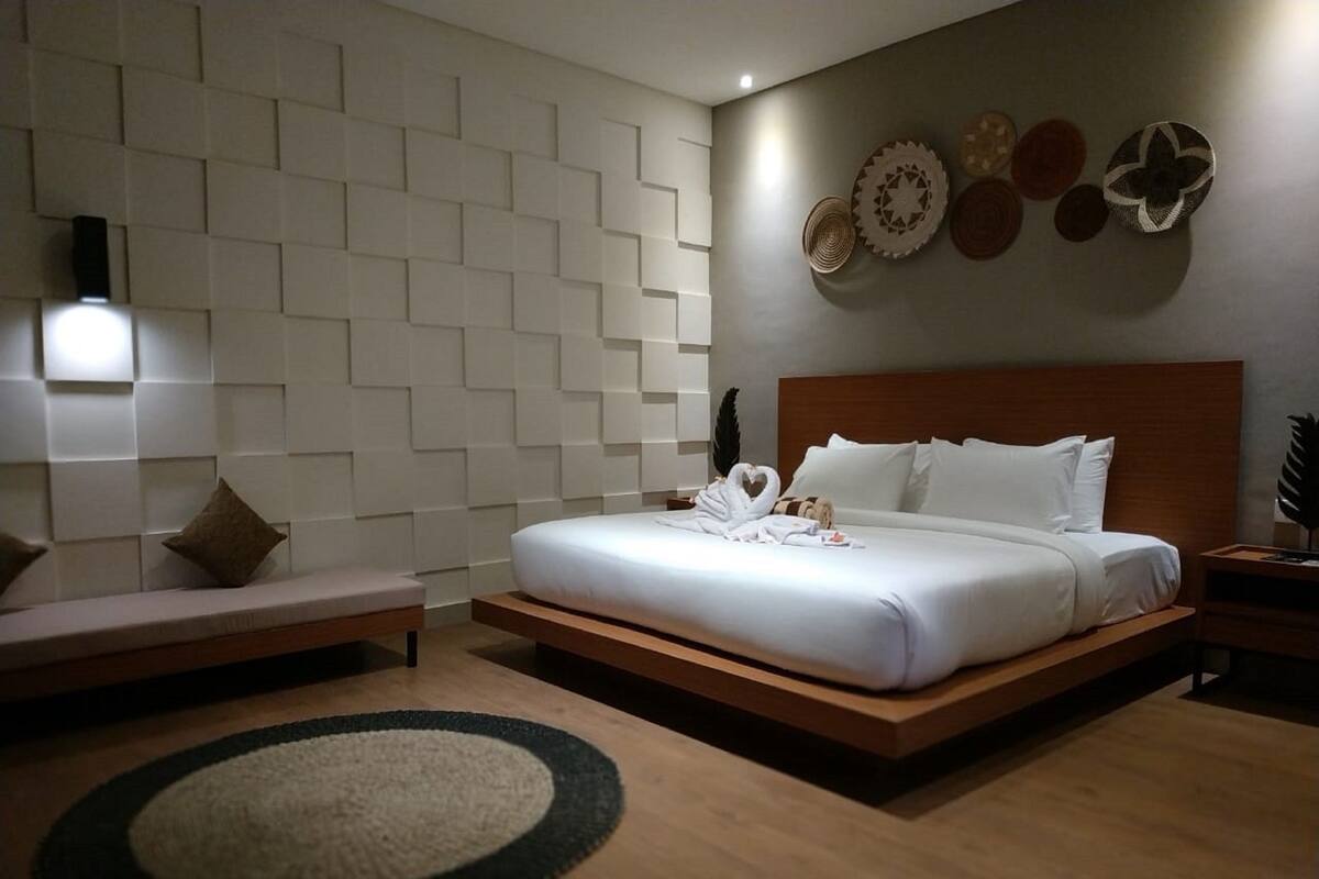 A modern hotel room with a large bed, a bench, and a wall decorated with circular patterns.