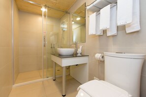 Une salle de bain moderne avec une douche à parois de verre, un lavabo blanc et des toilettes.