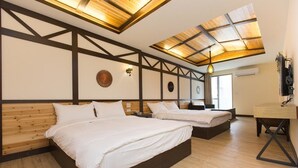 Een slaapkamer met twee bedden, houten balken, een dakraam en een bureau.