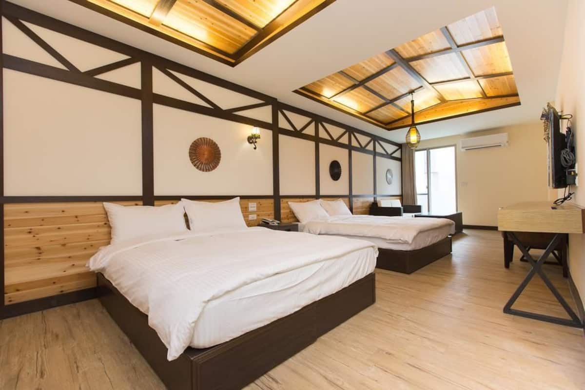 Un dormitorio con dos camas, vigas de madera, un tragaluz y un escritorio.