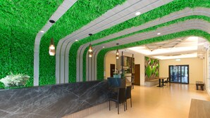 Een receptie met een groene wand, een marmeren balie en moderne verlichting.