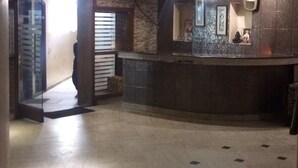 Un vestíbulo con un mostrador de recepción curvo, una escalera y un piso de baldosas.