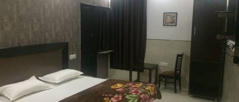 Una habitación de hotel con cama, una silla, una mesita y un armario.