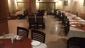 Un restaurante con varias mesas y sillas, dispuesto en un espacio amplio con suelo de baldosas.