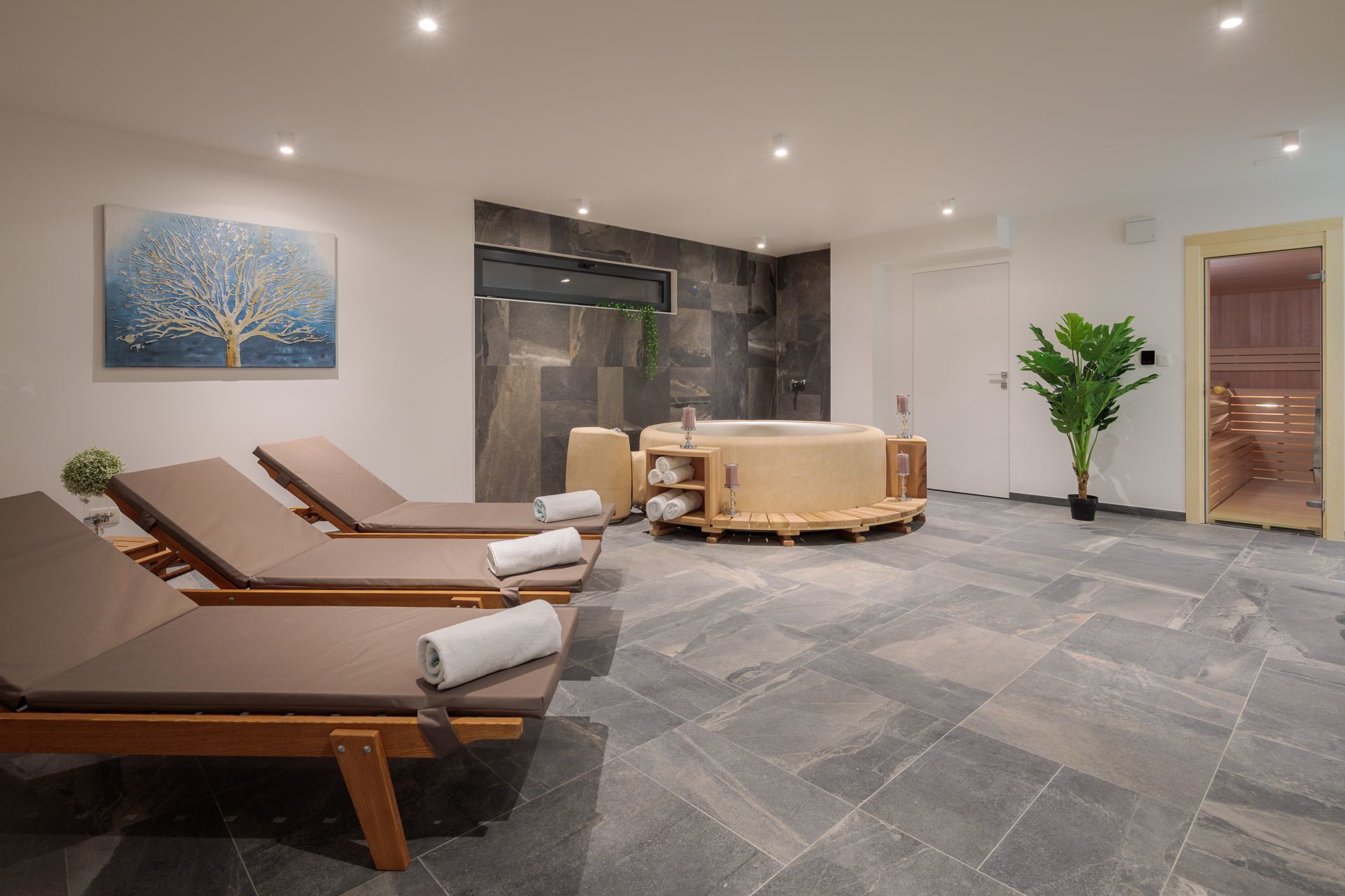 A spa area with reclining chairs, a hot tub, and a stone wall.