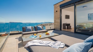 A modern outdoor seating area with a glass balustrade overlooking a coastal view. - Trogir Pearl Luxury Resort (Okrug)