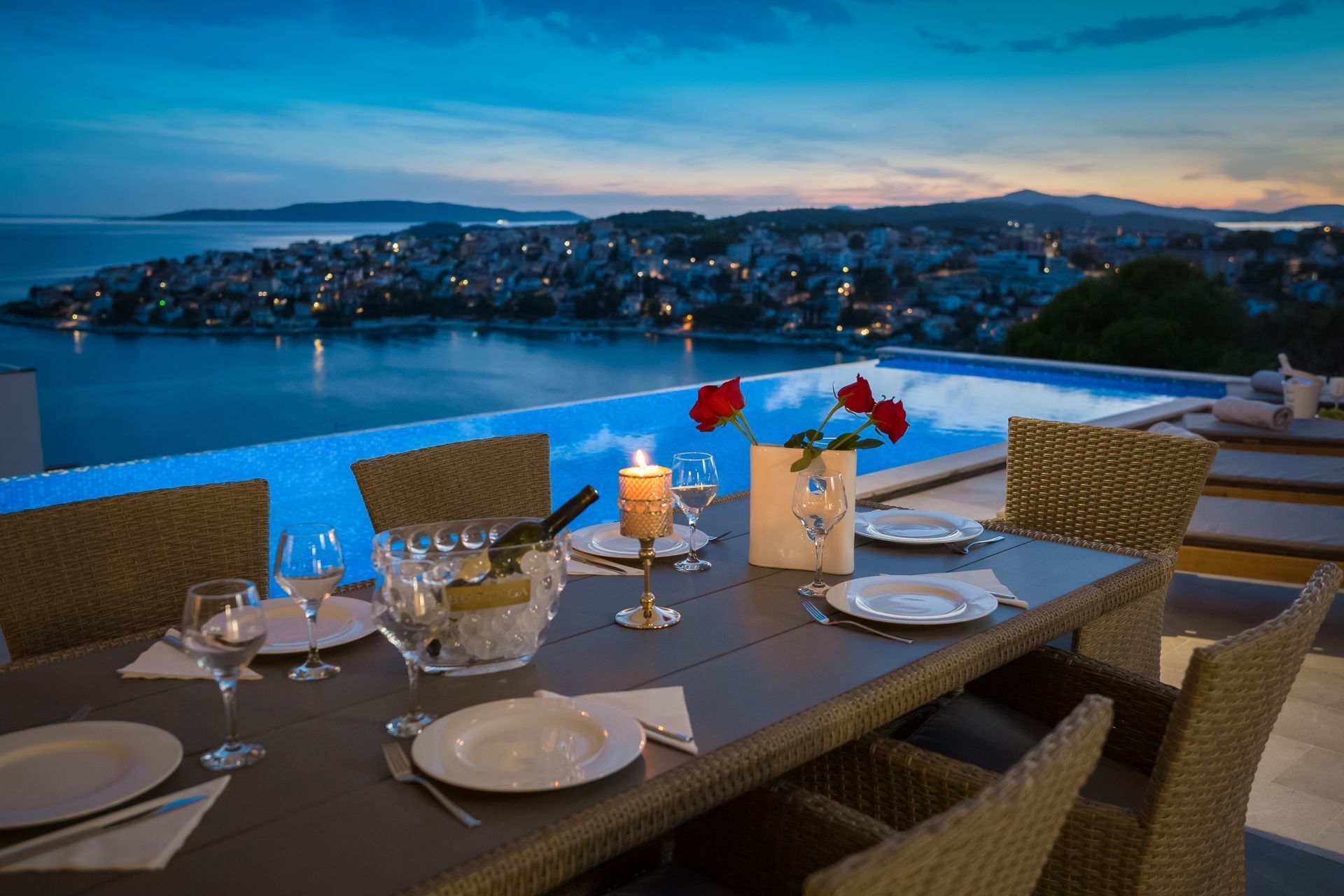 Une table dressée pour deux personnes, avec vue sur une ville côtière au crépuscule.