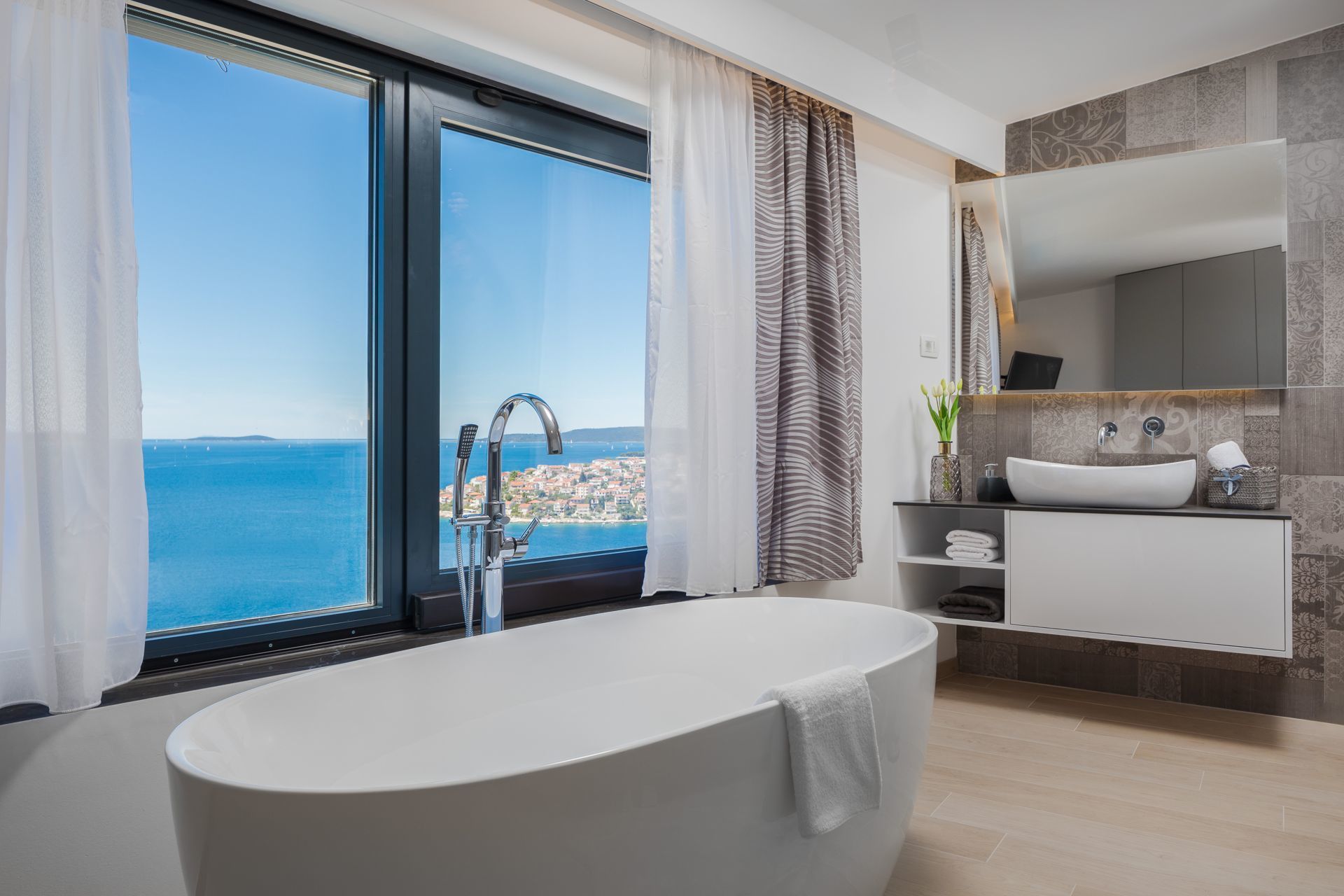 A modern bathroom with a large bathtub, a vanity with a sink, and a large mirror.