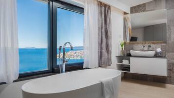 A modern bathroom with a large bathtub, a vanity with a sink, and a large mirror.