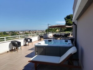 A rooftop terrace with a hot tub, lounge chairs, and outdoor seating. - La Terrazza di Harmakhis (Partanna)