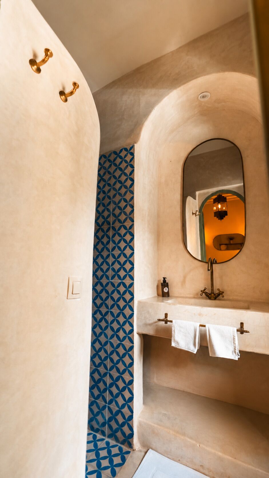 Ein Badezimmer mit einem Fliesenwand-Muster, einem Waschbecken mit Spiegel und einem Handtuchhalter.