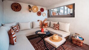 Uma sala de estar moderna com sofá, mesa de centro, painéis decorativos na parede e vista pela janela.