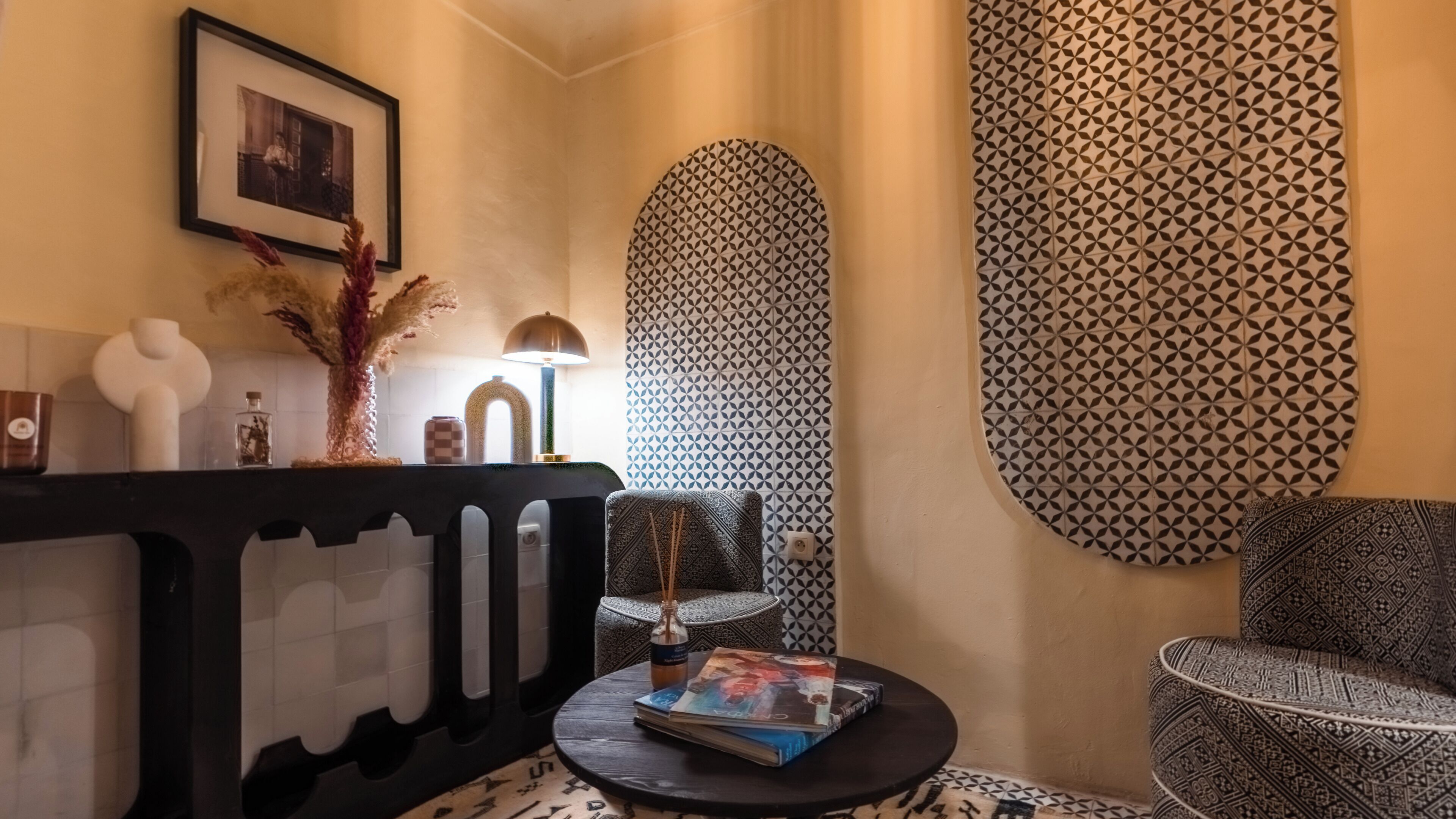 A modern interior with a black and white patterned wall, a round table with a magazine, and a decorative vase.