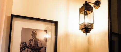 A framed black and white photograph on a wall, a wall-mounted light fixture, and a door frame.