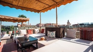 A rooftop terrace with outdoor seating, a table, and a view of the cityscape. - Riad Dar Tiflet (Marrakech)