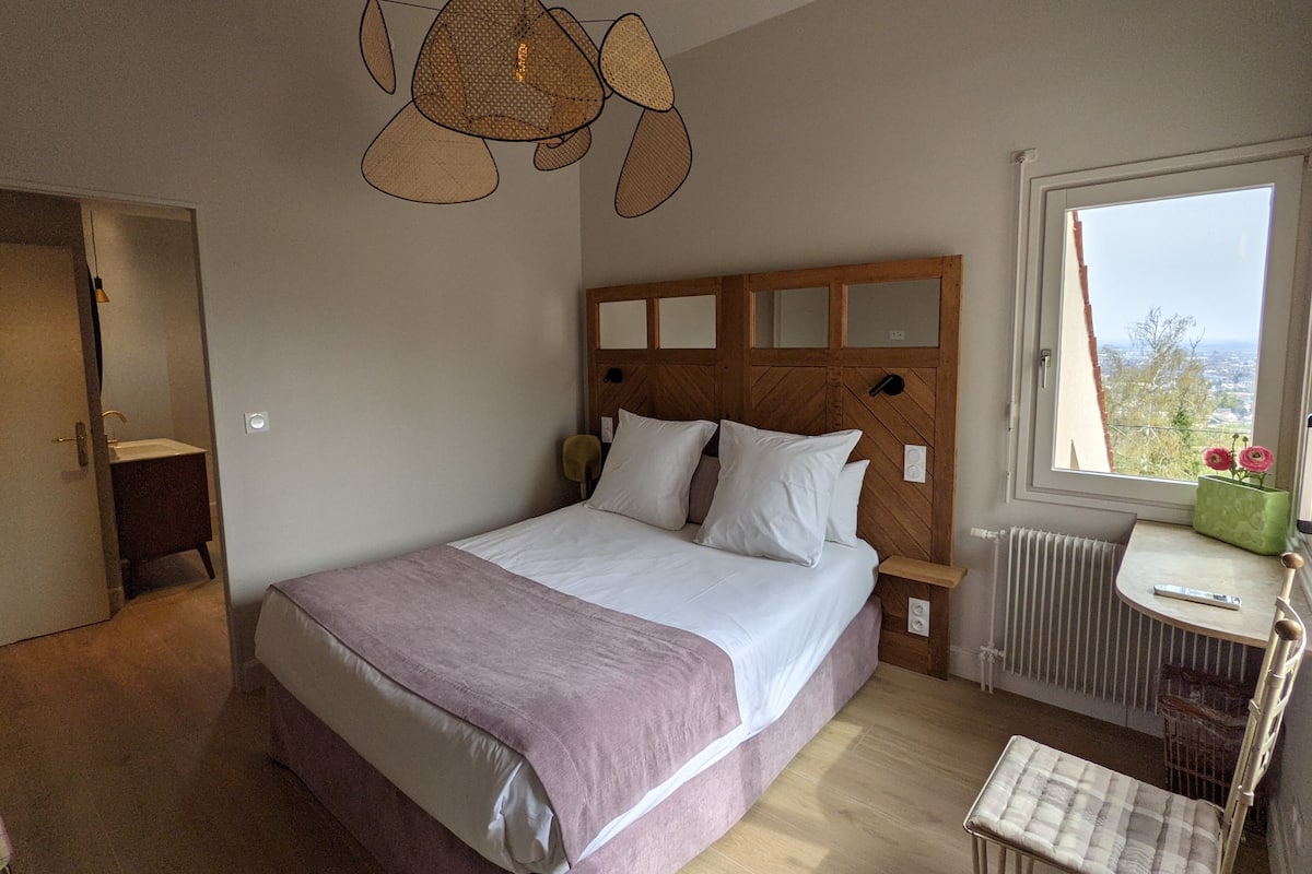 Ein Schlafzimmer mit Bett, Nachttisch, Stuhl und einem Fenster mit Blick.