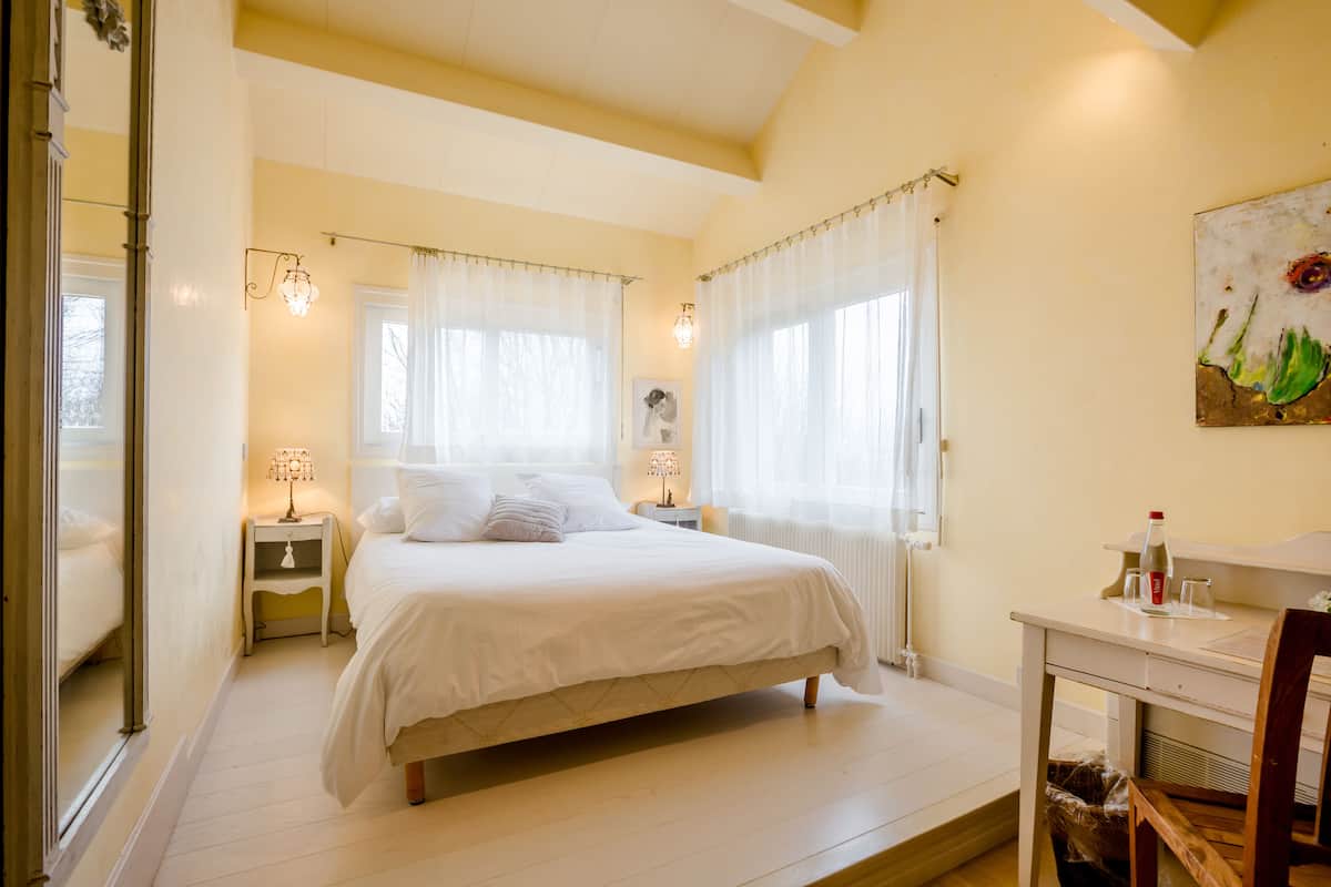 Ein Schlafzimmer mit einem Bett, Nachttischen, einem Schreibtisch und einem Sessel.