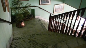 A staircase with a wooden railing, a potted plant, and framed pictures on the walls. - Hotel Vecchia Rimini (Comacchio)