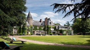 A large, historic building with a prominent tower, surrounded by well-maintained lawns and outdoor seating areas. - Les Hauts de Loire (Veuzain-sur-Loire)