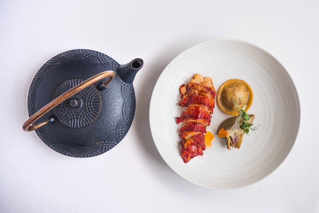 Un plato blanco con comida y una tetera negra.