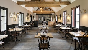A spacious dining area with high ceilings and exposed beams, featuring multiple tables and chairs arranged for dining. - Les Hauts de Loire (Veuzain-sur-Loire)
