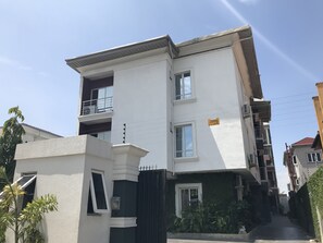 A multi-story building with balconies, a gated entrance, and a clear sky. - H3 Luxury Cottage (Lekki)