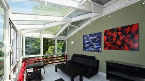 A modern living room with a glass ceiling, a black sofa, a coffee table, and two abstract paintings on the wall. - Art Hotel Weimar (Weimar)
