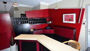 A compact kitchen with red and black cabinetry, a wooden countertop, and pendant lighting. - Art Hotel Weimar (Weimar)
