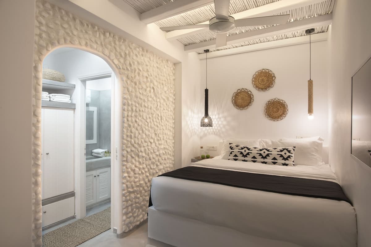 A modern bedroom with a bed, a ceiling fan, and decorative wall hangings.
