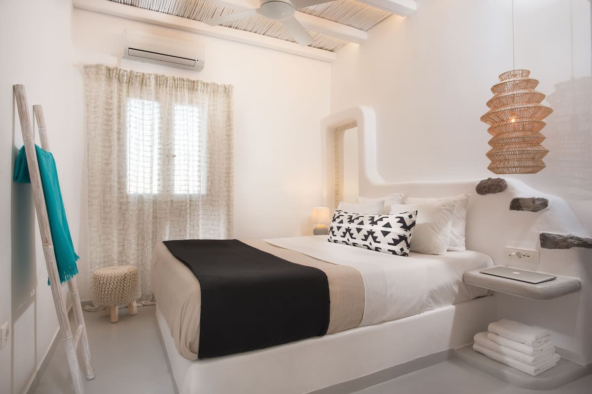 A modern bedroom with a bed, bedside table, and a hanging light fixture.