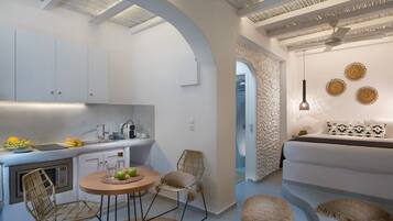 Una cocina compacta con comedor, que incluye una mesa redonda, sillas y un microondas.