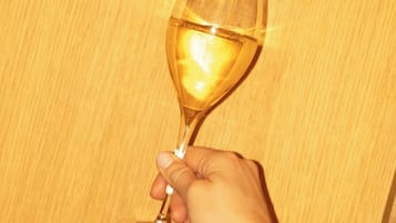 Una mano che tiene un bicchiere di vino su sfondo in legno.