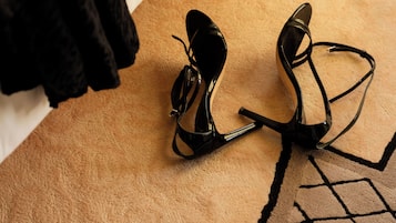 Un paio di scarpe con tacco nero su un tappeto beige con motivo geometrico.